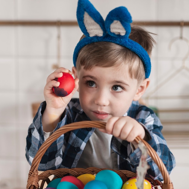 Adorable little boy holding basket with easter eggs