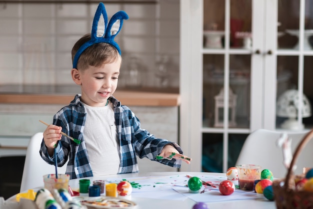 Free photo adorable little boy painting eggs for easter