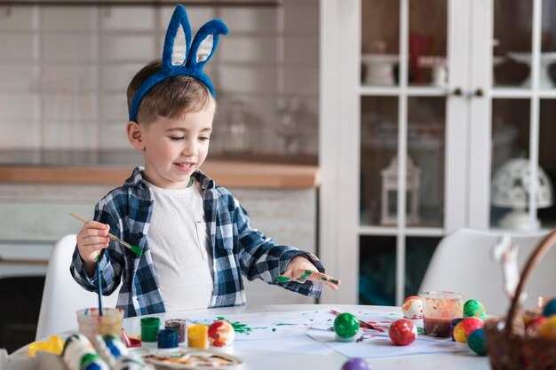 Adorable little boy painting eggs for easter