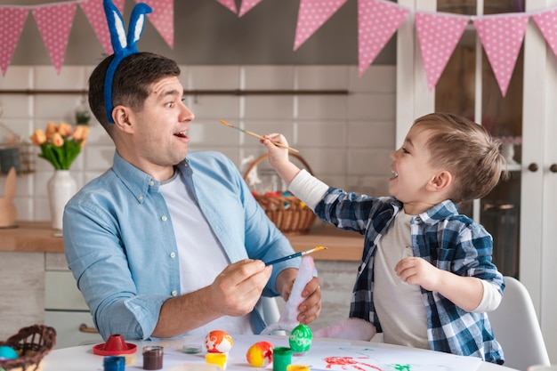 Adorable little boy trying to paint his father