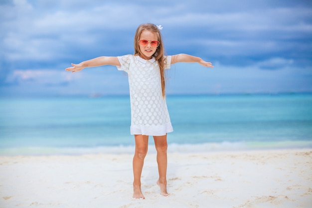 Очаровательная маленькая девочка на пляже на летних каникулах