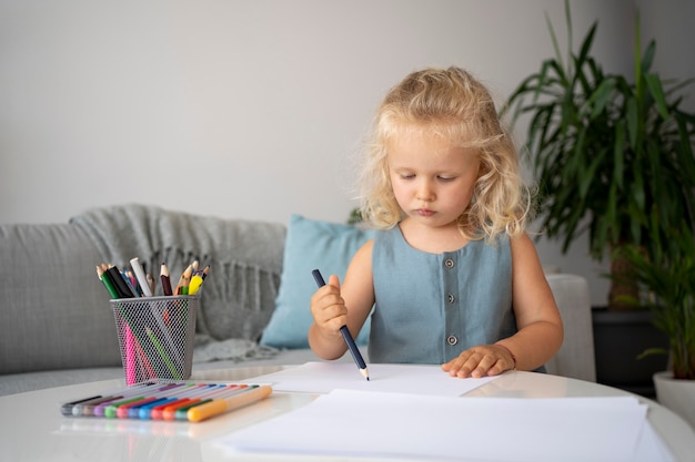 Бесплатное фото Очаровательная маленькая девочка, рисование на бумаге дома