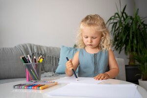 Free photo adorable little girl drawing on paper at home