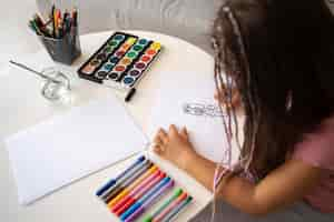 Free photo adorable little girl drawing on paper at home