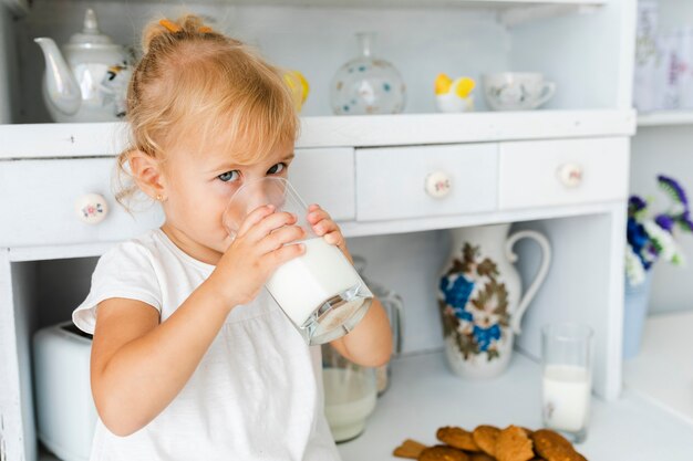 Очаровательная маленькая девочка пьет молоко
