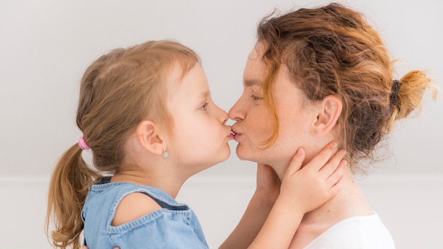 Очаровательная маленькая девочка целует маму