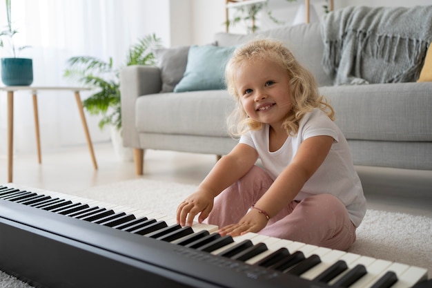 Adorable little girl learning how to play piano at home