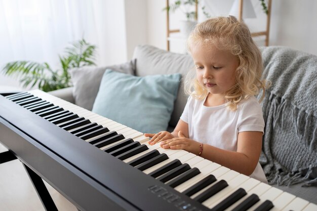 Adorable little girl learning how to play piano at home