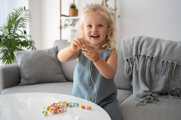 Adorable little girl making accessories with different colorful balls