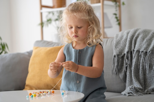 Adorable little girl making accessories with different colorful balls