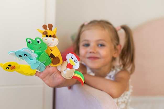 Adorable little girl playing with her puppets at home