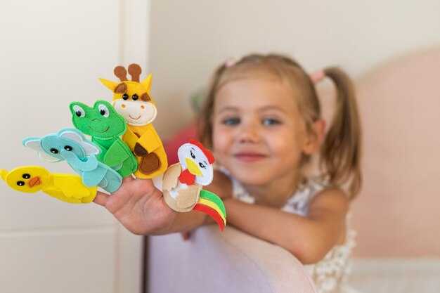 Adorable little girl playing with her puppets at home