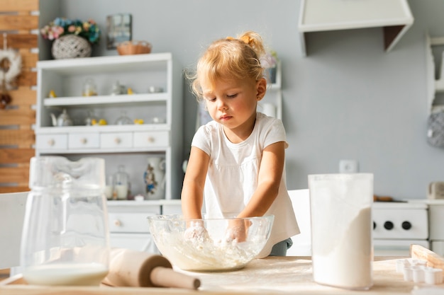 Free photo adorable little girl preparing dough