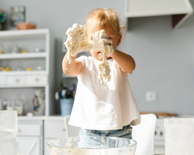 Adorabile bambina con le mani piene di pasta