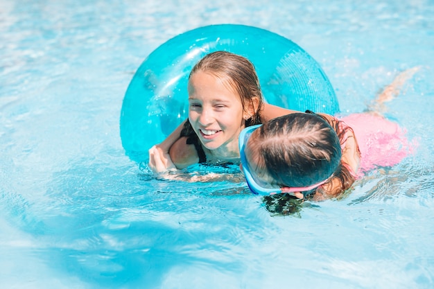 Очаровательные маленькие девочки играют в открытом бассейне на отдыхе