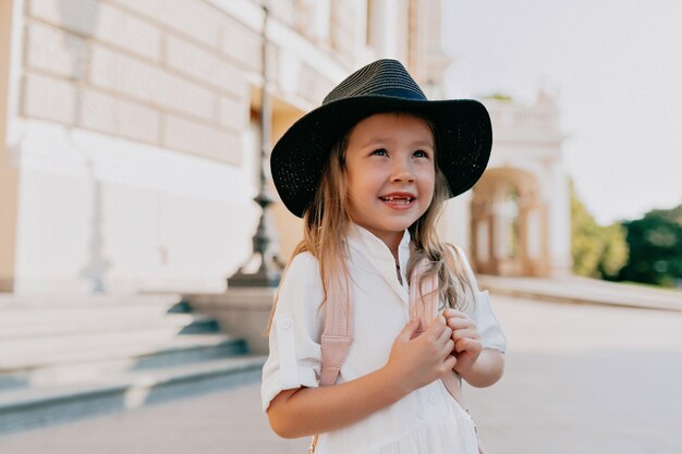 Free photo adorable lovely little girl in hat exploring the city