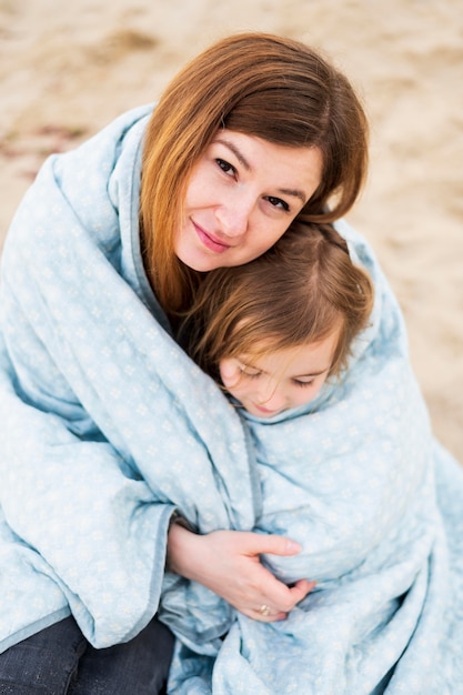 Adorable mother and daughter in blanket