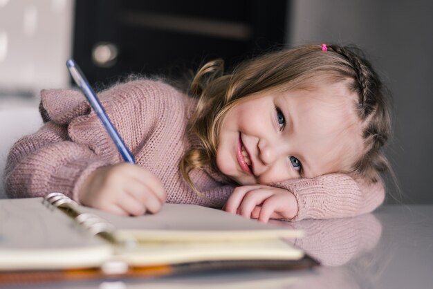 テーブルでペンで描く愛らしい幼児少女