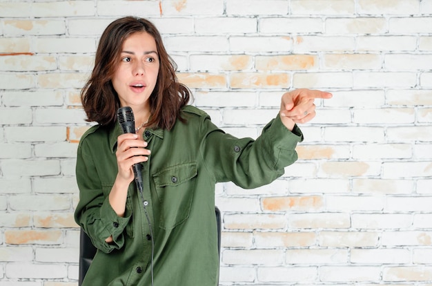 Free photo adorable singer holding her mic and point finger aside