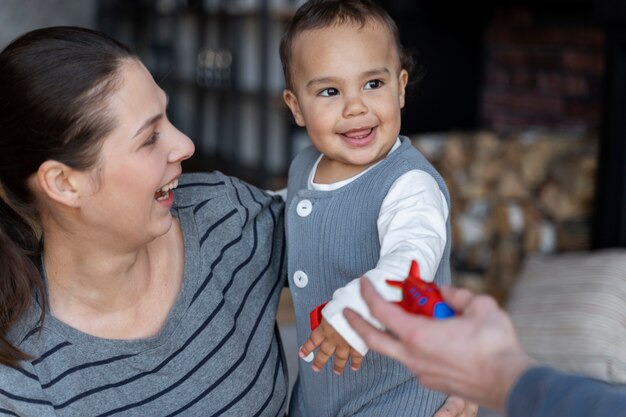 Adorable smiley held by his mother and offered toy