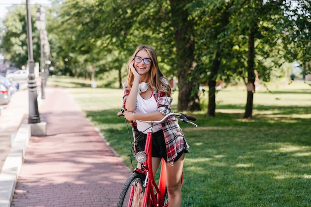 자전거와 함께 공원에서 포즈를 취하는 사랑스러운 웃는 소녀. 자연에 포즈를 취하는 편안한 숙 녀의 야외 사진.