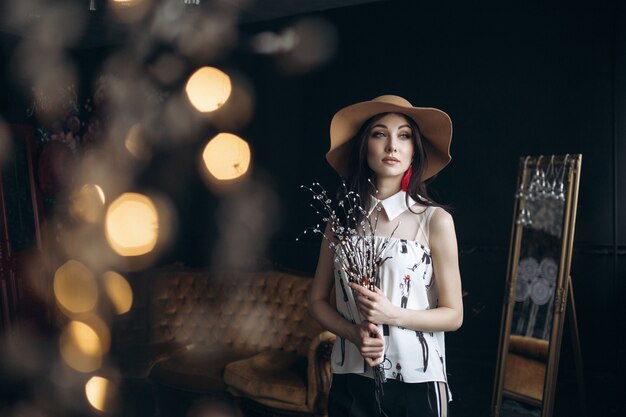 Adorable smiling woman in beige hat and with fashion look poses in the studio