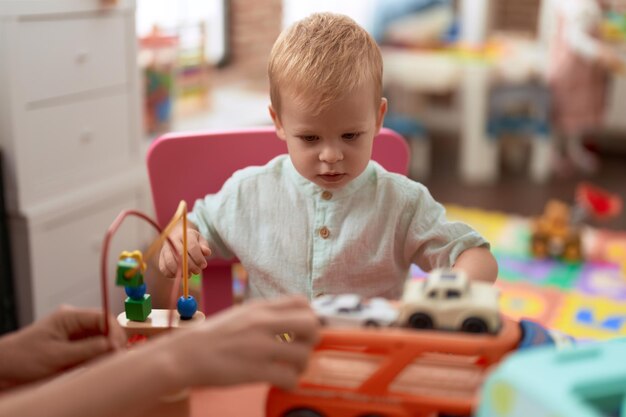 Adorable toddler playing with car toy sitting on table at kindergarten