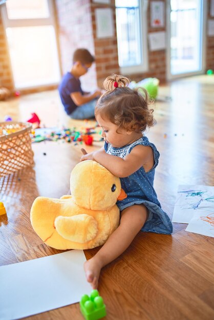 Adorable toddlers smiling happy Sitting on the floor playing around lots of toys at kindergarten