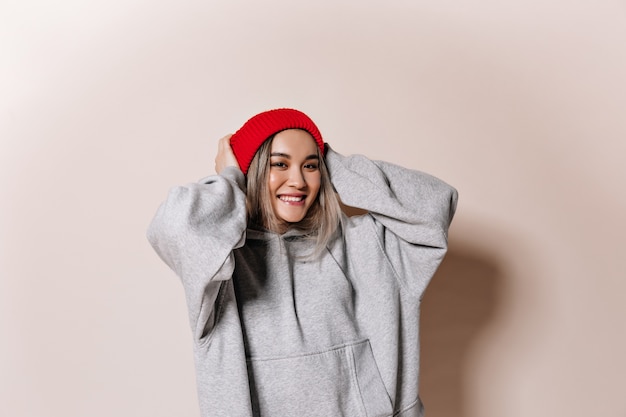 Free photo adorable woman in red cap and sweatshirt smiling on isolated wall