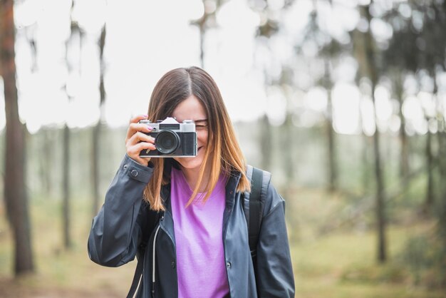 Adorable woman taking photos in forest