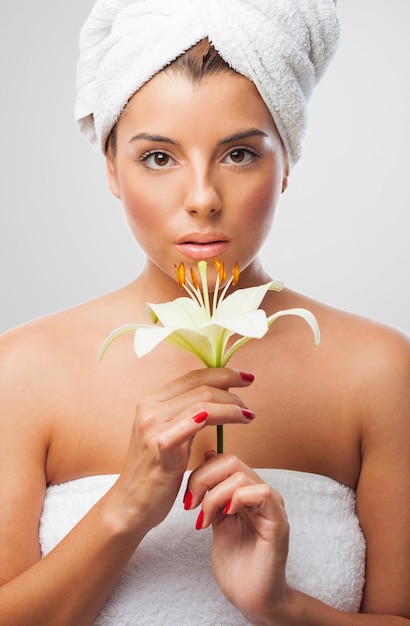 Adorable woman in towel with lily flower