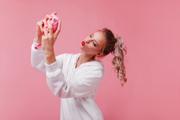 Adorable woman with curly hair posing with kissing face expression