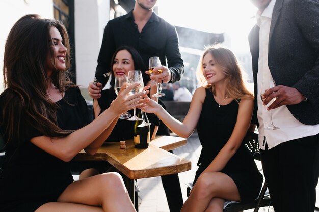 Adorable women clink glasses at party and smiling