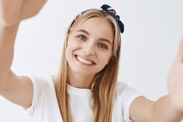 Adorable young blond girl posing against the white wall