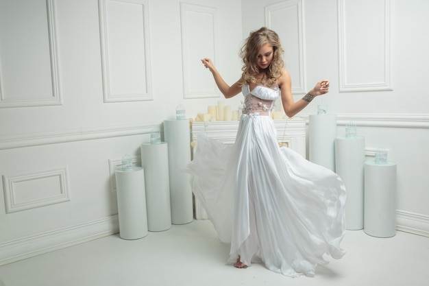 Adorable young blonde wearing beautiful white dress and raised her hands High quality photo