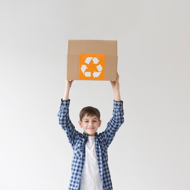 Free photo adorable young boy holding recycling box