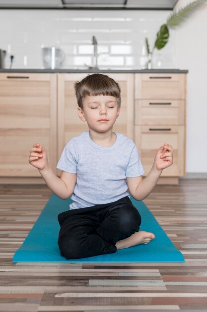 Adorable young boy meditating at home