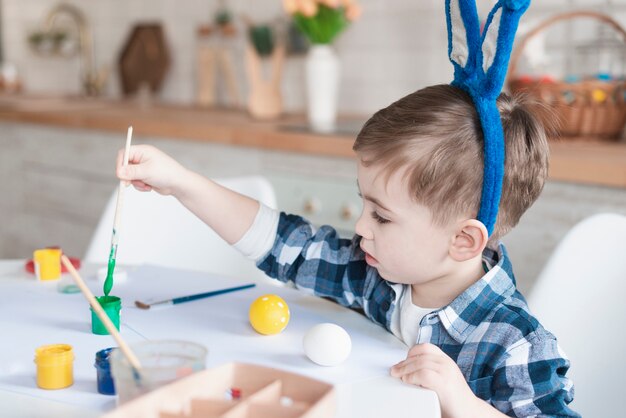 Adorable young boy painting easter eggs