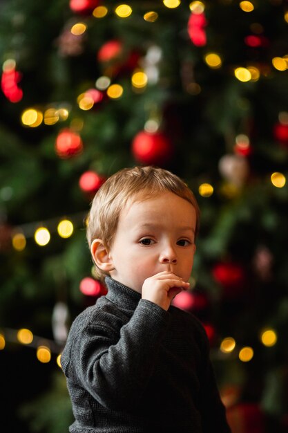 Очаровательный мальчик играет с рождественскими игрушками