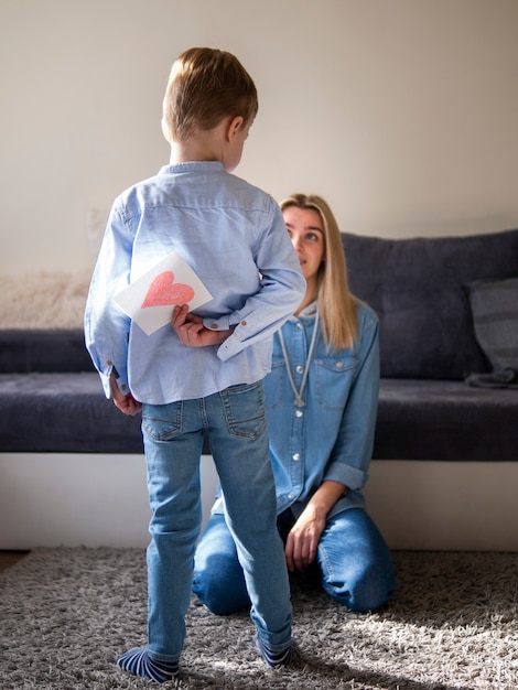 Adorable young boy surprising mom with flowers