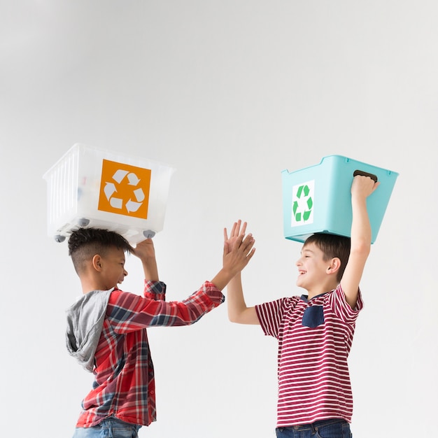 Free photo adorable young boys holding recycle boxes