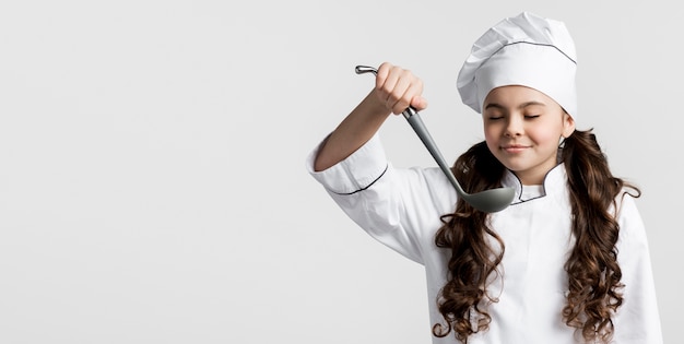 Adorable young chef holding soup ladle