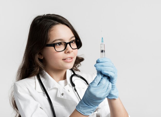 Adorable young girl with surgical gloves and syringe