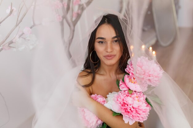 Adorable young lady hugging her flowers under the tulle High quality photo