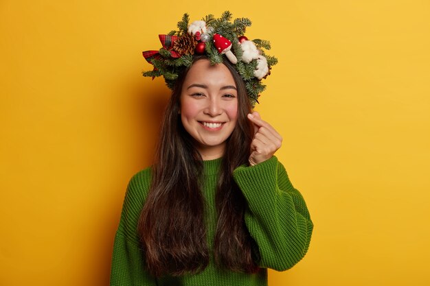 Adorable young lady smiles pleasantly wearing festive wreath on head