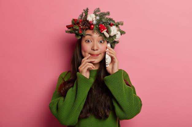 Adorable young lady smiles pleasantly wearing festive wreath on head