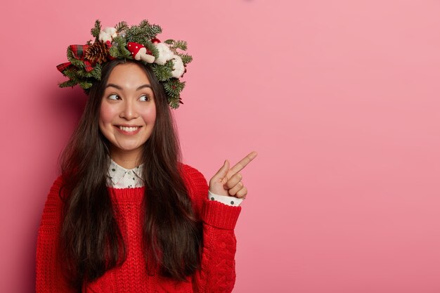 Adorable young lady smiles pleasantly wearing festive wreath on head