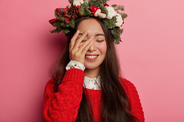 Adorable young lady smiles pleasantly wearing festive wreath on head