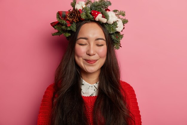 Adorable young lady smiles pleasantly wearing festive wreath on head