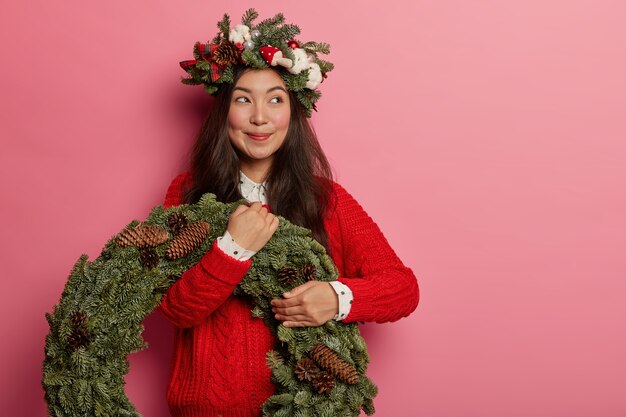 Adorable young lady smiles pleasantly wearing festive wreath on head